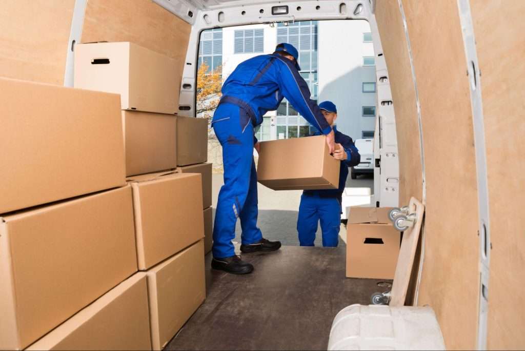Young movers loading cardboard boxes in truck